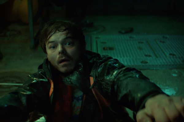 Scène de la série Below sur Netflix : un homme dans la cale sombre d'un bateau, éclairé à la lampe