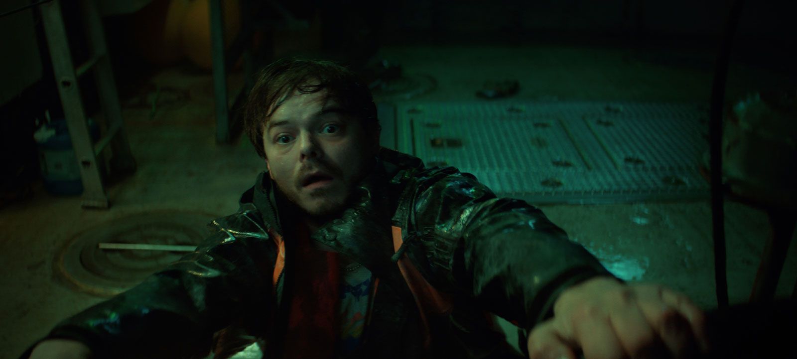Scène de la série Below sur Netflix : un homme dans la cale sombre d'un bateau, éclairé à la lampe