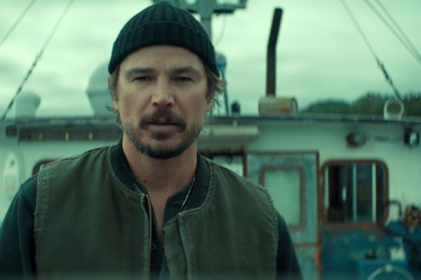 Scène de la série Below sur Netflix : un pêcheur en bonnet devant son chalutier, sur la côte de Terre-Neuve