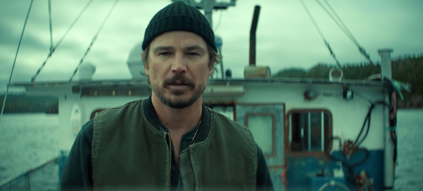 Scène de la série Below sur Netflix : un pêcheur en bonnet devant son chalutier, sur la côte de Terre-Neuve