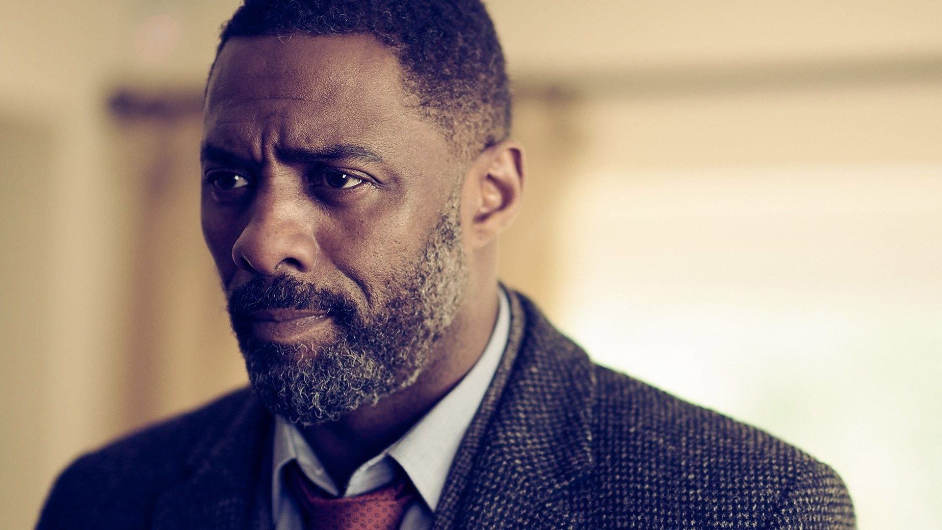 Idris Elba dans le rôle du commissaire John Luther, manteau de tweed gris, dans la série Luther